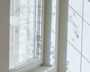 Double vitrage avec croisillons, les ombres extérieures se reflètent sur le mur blanc