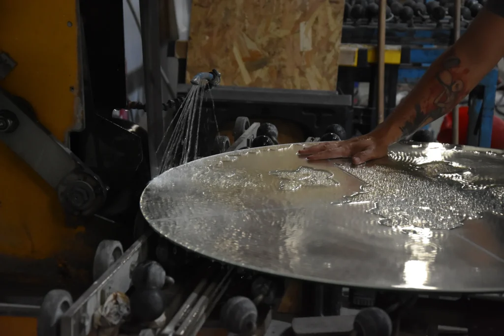 Technicien polissant un miroir rond sur une machine dans l'atelier de La Vitrerie