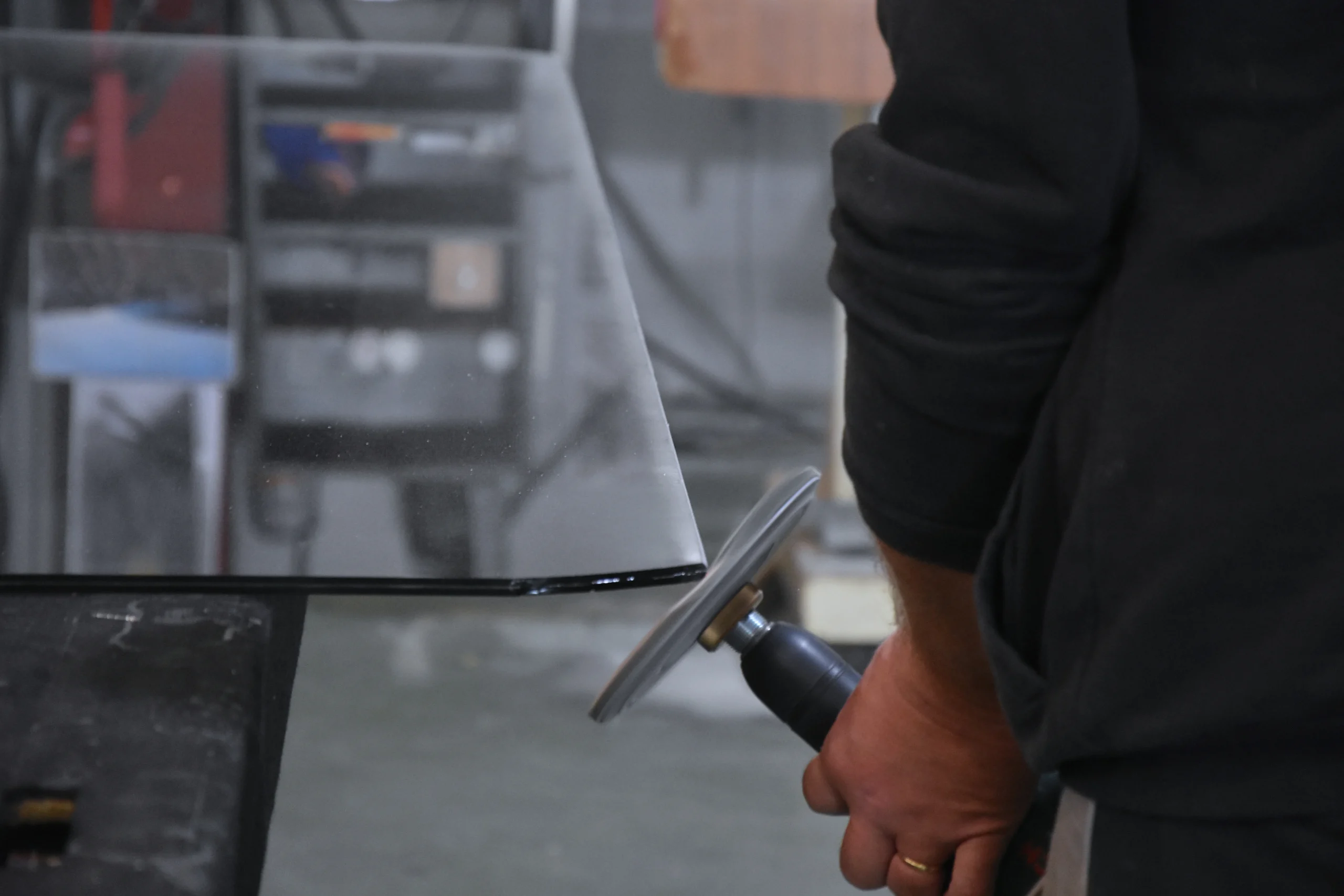 Dans l'atelier de La Vitrerie, un technicien façonne le verre feuilleté avec un outil spécialisé