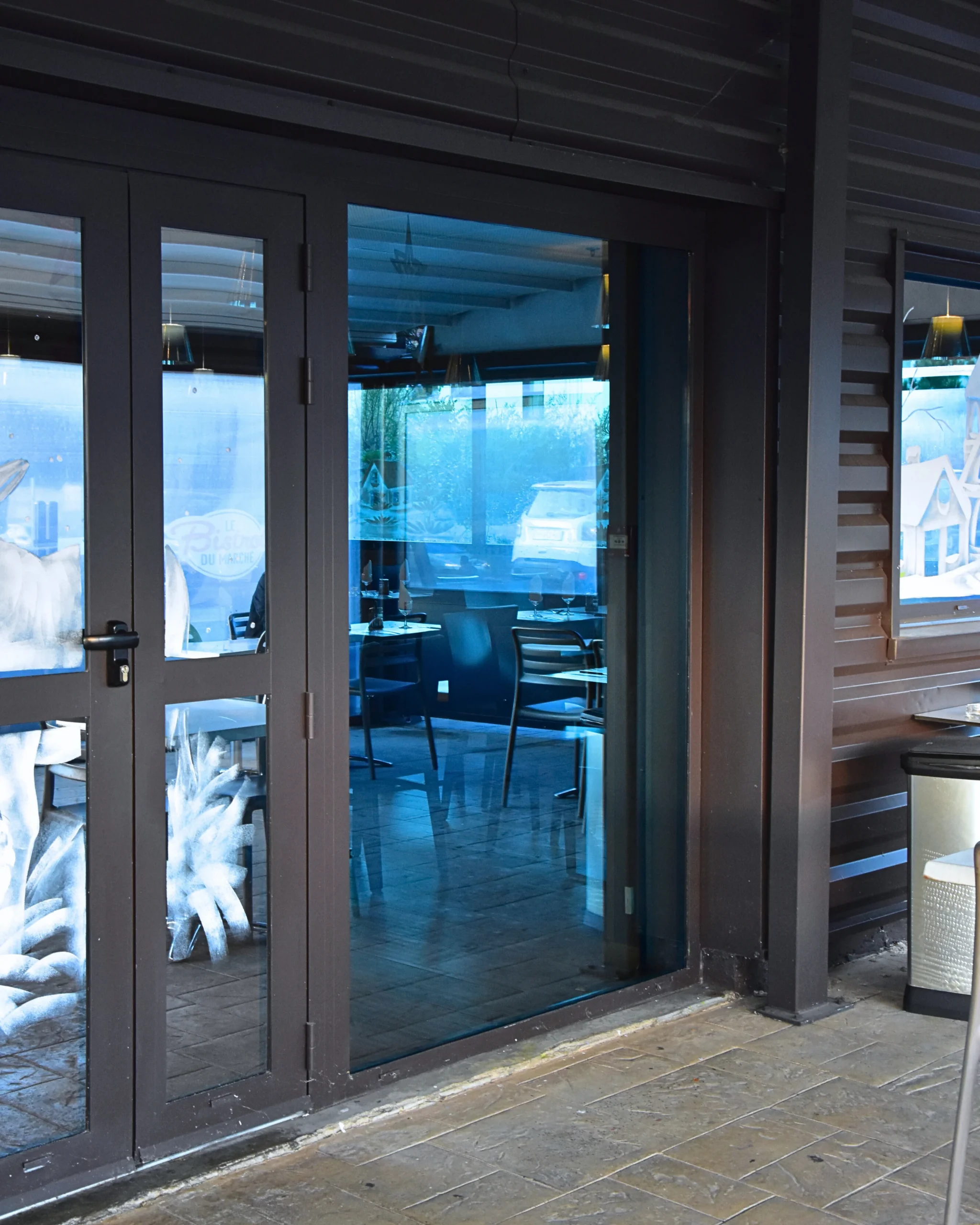 Porte vitrée d'un restaurant avec un verre stopsol bleu